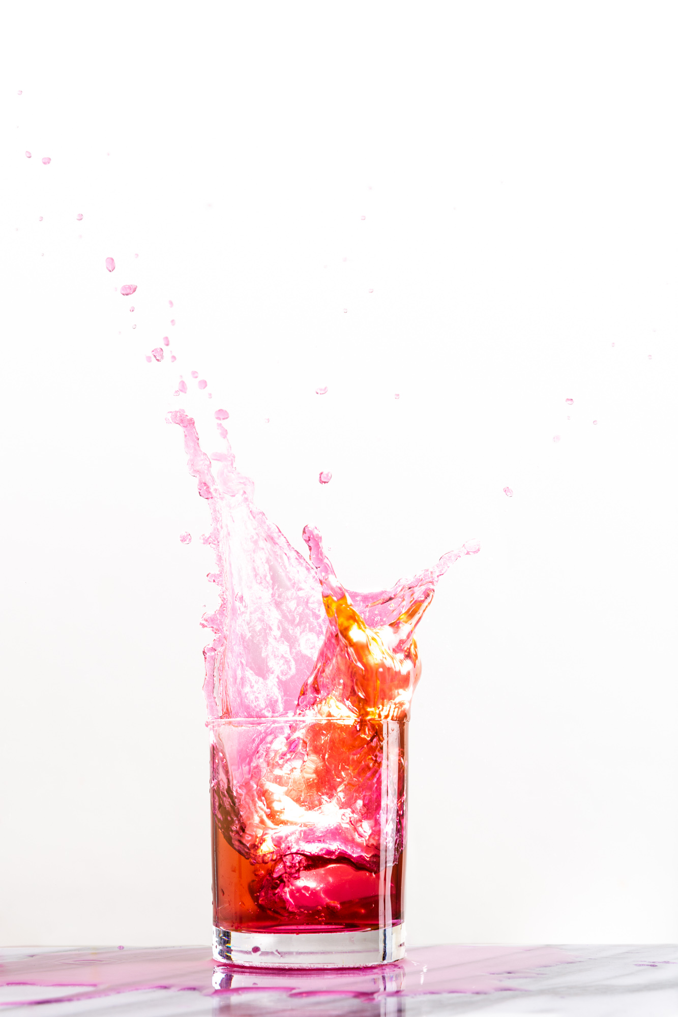 Colorful drink splashes out of a cocktail glass