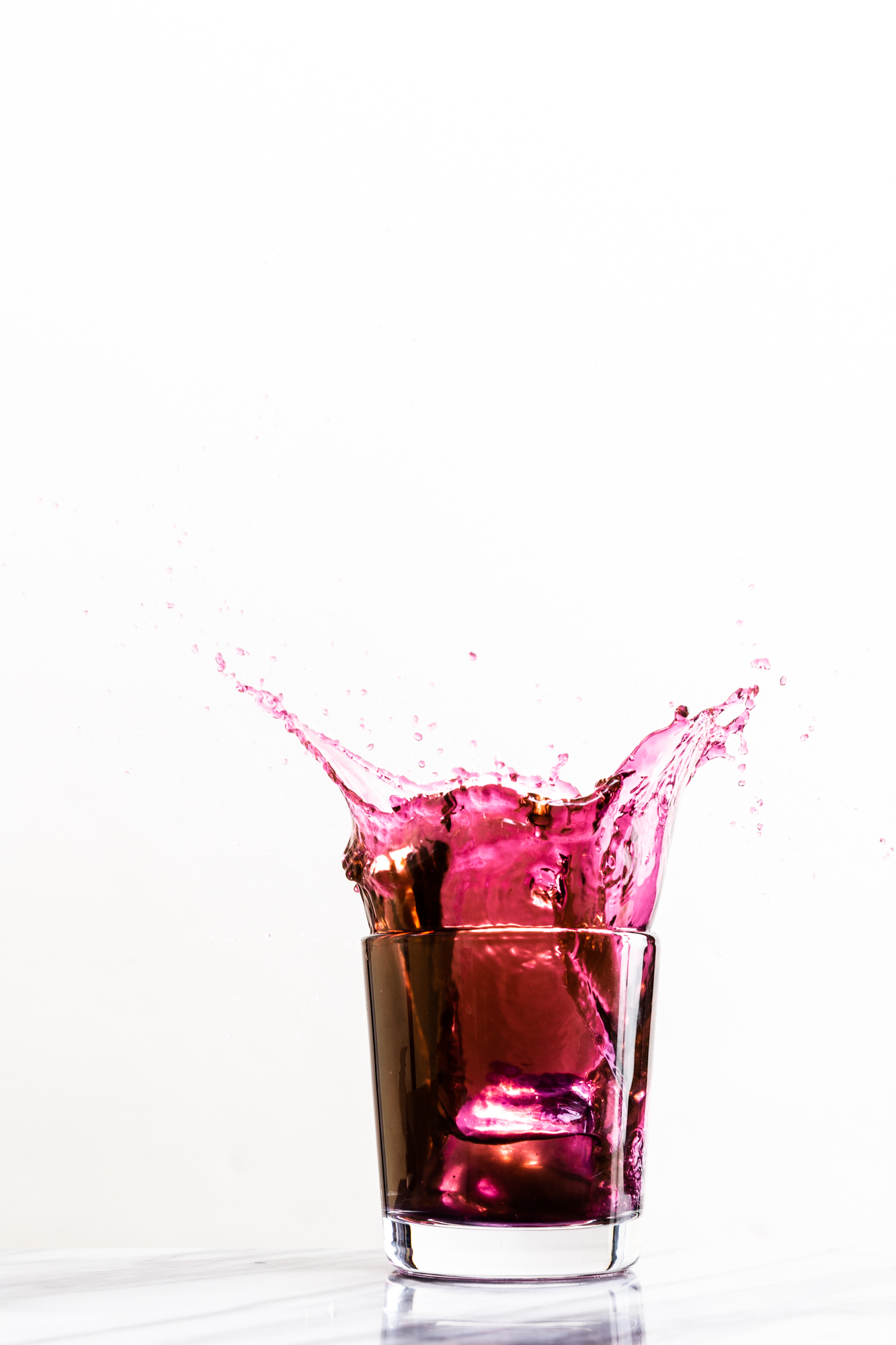 Cocktail splashes out of glass against white background