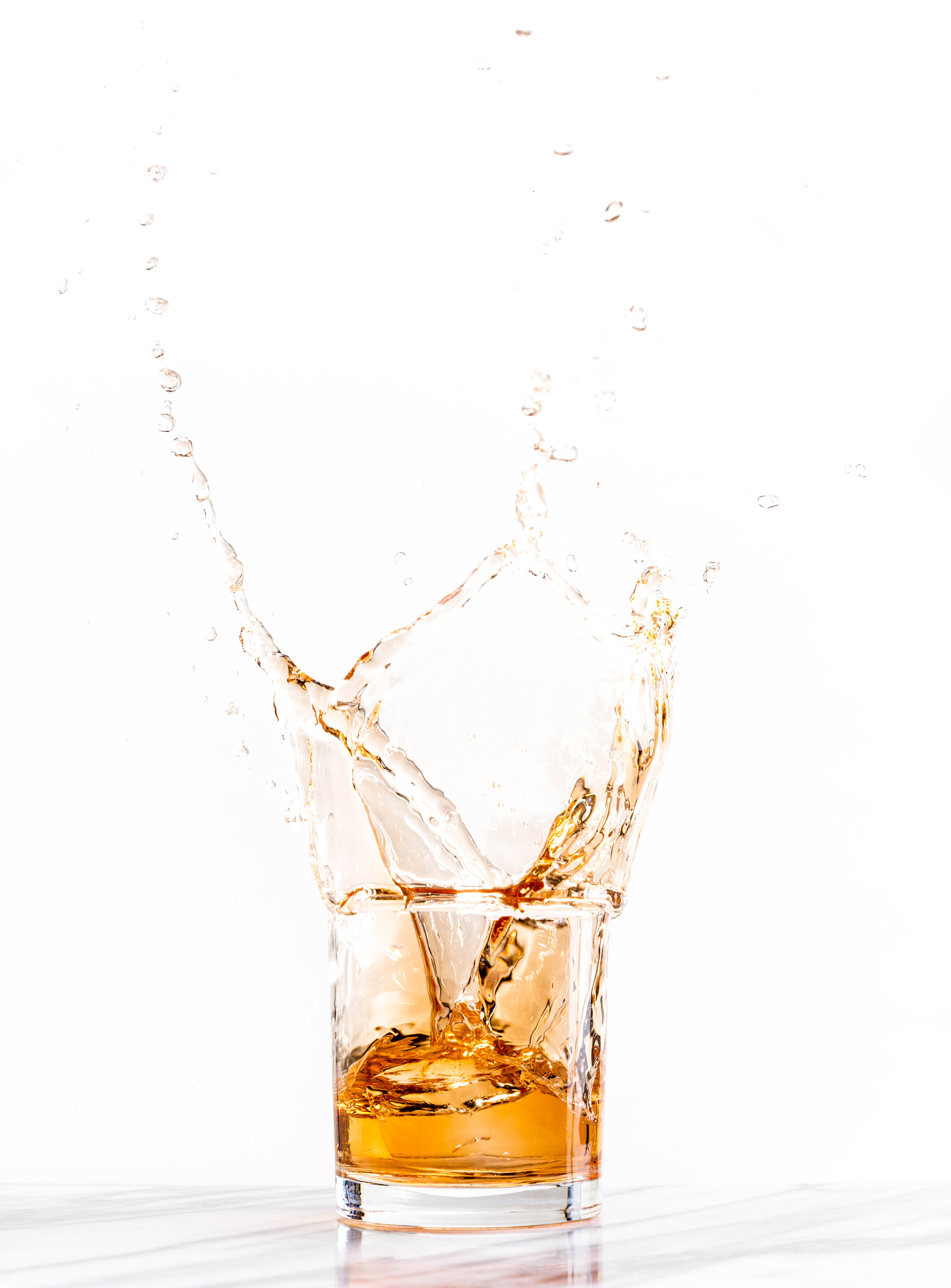 Ice cube dropped into glass of liquor
